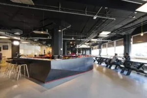 Moderne bedrijfsruimte aan de Anthony Fokkerweg met een centrale bar, industriële uitstraling en lange zitbanken bij de ramen.